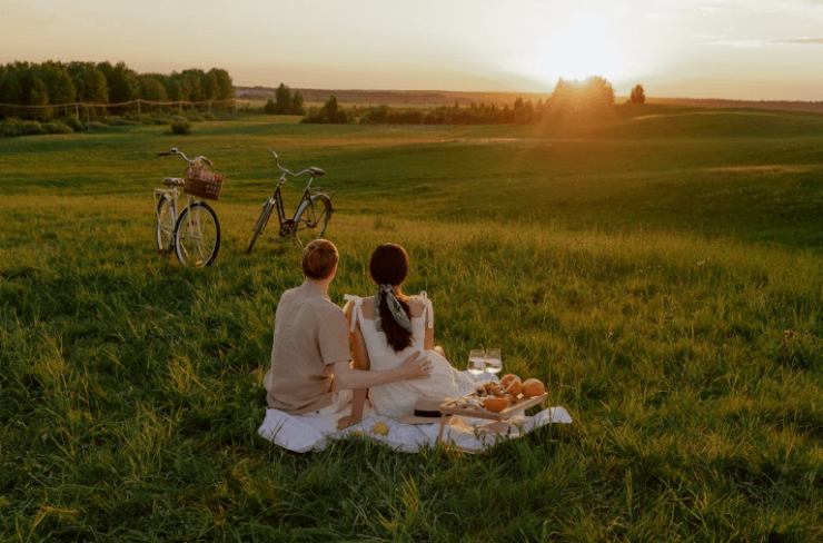 Ein Mann und eine Frau sitzen auf einer Wiese und machen ein Picknick